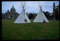 Teepees and a totem pole on the front lawn of the enormous stone parliament building, Victoria, British Columbia.
